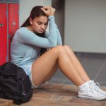 sad-schoolgirl-sitting-locker-room-school-87397016